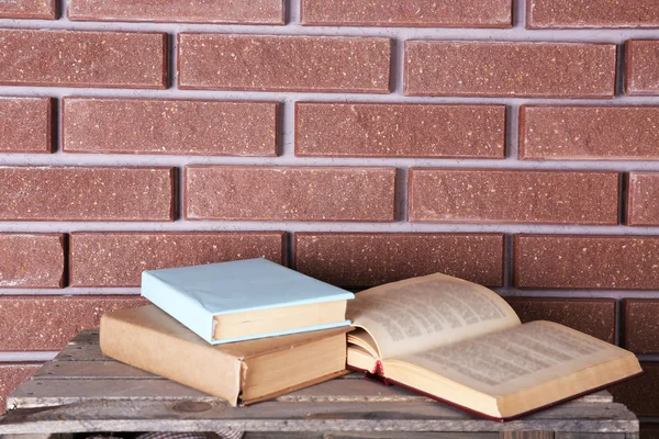 Open books  in front of brick wall — Stock Photo, Image