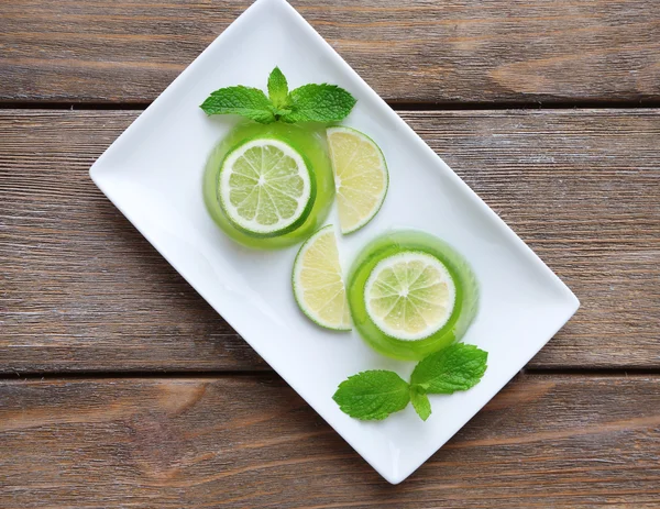 Grønn gele med mynteblader og sitronkalkskiver på trebakgrunn – stockfoto