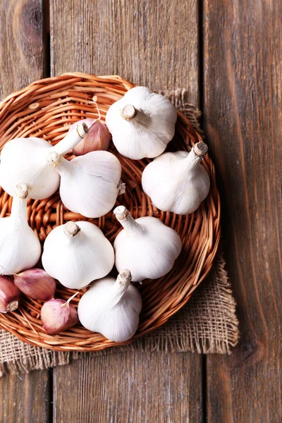 Fresh garlic on wicker mat, on wooden background — Stock Photo, Image