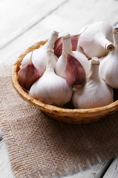 Fresh garlic in wicker basket, on wooden background — Stock Photo, Image