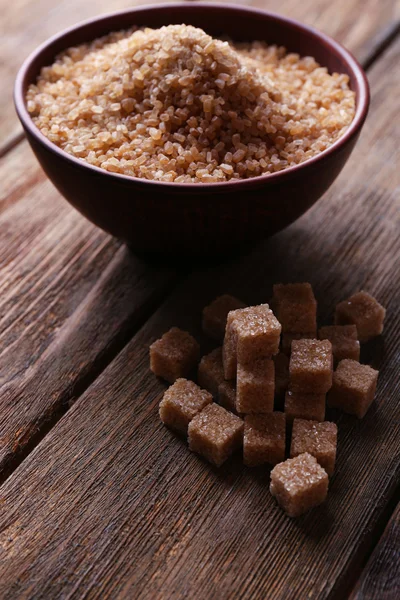 Cubes de sucre brun et sucre cristallin dans un bol sur fond en bois — Photo