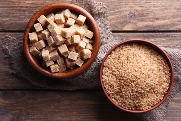 Cubes de sucre brun et sucre cristallin dans un bol sur fond en bois — Photo