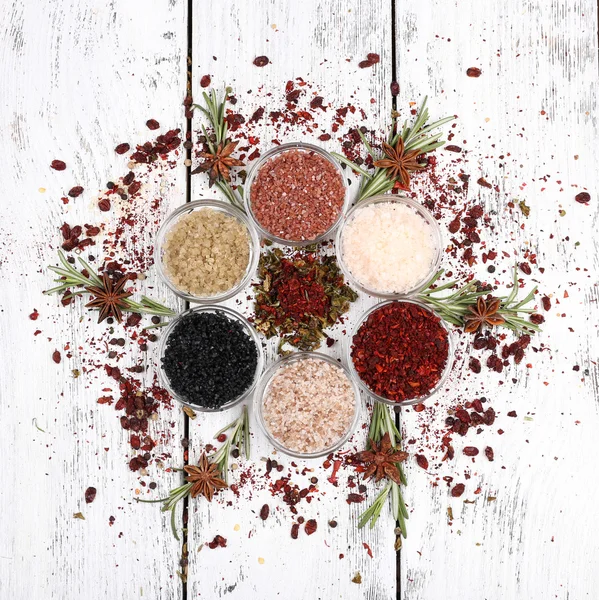 Spices in glass round bowls with herbs on wooden background