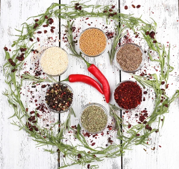 Spices in glass round bowls with herbs and chilly pepper on wooden background — Stock Photo, Image