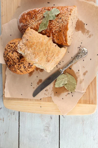 Pan recién horneado, sobre tabla de cortar, sobre fondo de madera — Foto de Stock