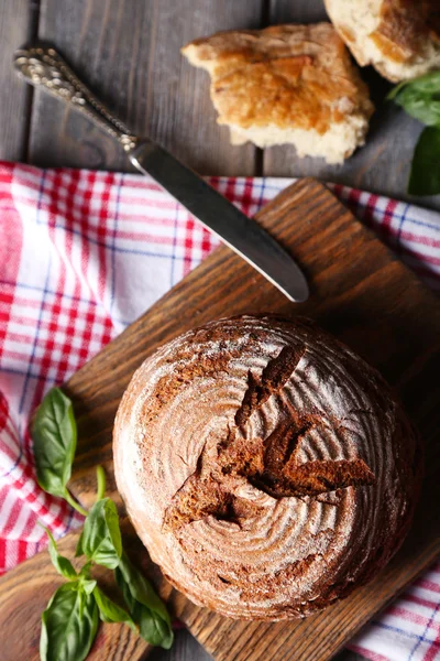 신선한 구운 빵과 신선한 바 질 나무 배경에 절단 보드 — 스톡 사진