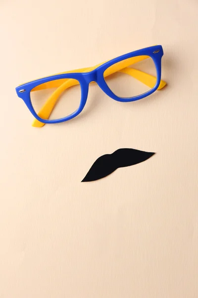 Glasses and mustache forming man face on beige background — Stock Photo, Image