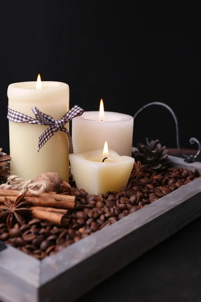 Candles on vintage tray with coffee grains and spices, bumps on wooden table, on dark background — Stock Photo, Image