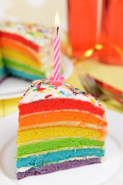 Delicioso pastel de arco iris en el plato en la mesa sobre fondo brillante —  Fotos de Stock