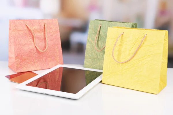 Computer tablet met credit card en papieren zakken op tafel op lichte achtergrond — Stockfoto