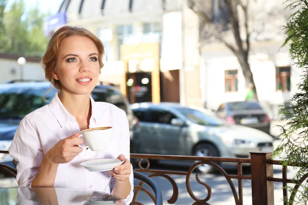 Beautiful young woman sitting in cafe — Stock Photo, Image
