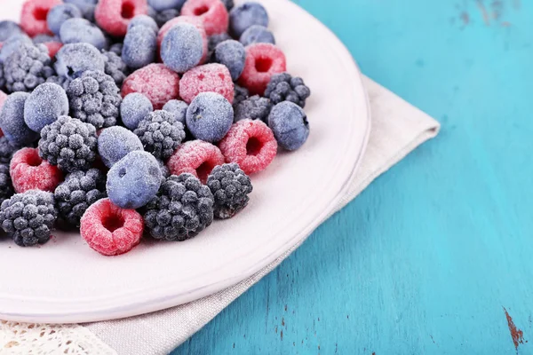 Iced berries on plate, on color wooden background — Stock Photo, Image