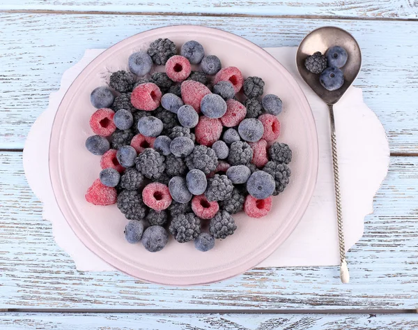 Iced berries on plate, on color wooden background — Stock Photo, Image