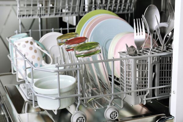 Открытая посудомоечная машина с чистой посудой в ней