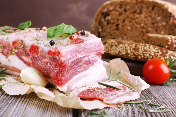 Raw bacon with bread and spices on wooden table — Stock Photo, Image