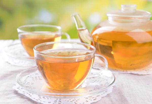 Teekanne und Tassen Tee auf Tisch auf hellem Hintergrund — Stockfoto