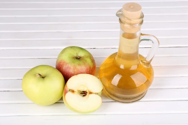 Vinaigre de cidre de pomme en bouteille de verre et pommes fraîches mûres, sur table en bois — Photo