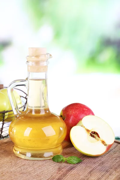 Cuka sari apel dalam botol kaca dan apel matang segar, di atas meja kayu, di latar belakang alam — Stok Foto