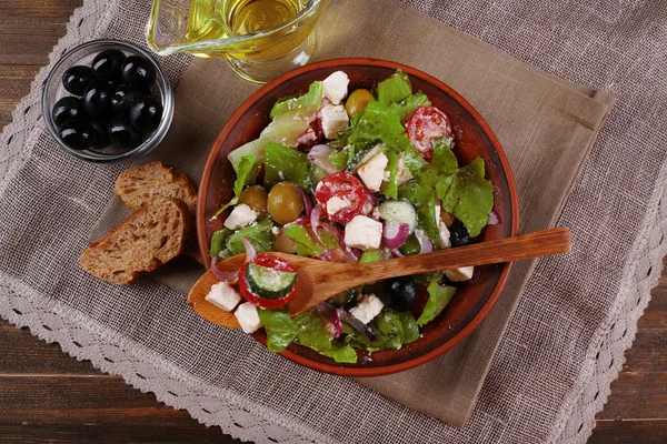 Kom van Griekse salade geserveerd op servet op houten achtergrond close-up — Stockfoto
