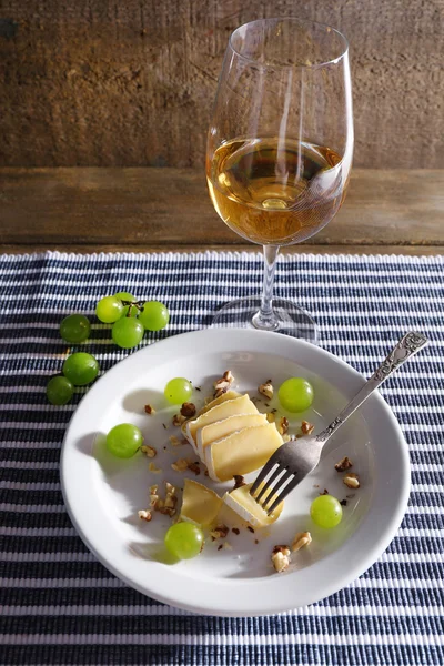 Schönes Stillleben mit Wein, Käse und reifen Trauben auf Holzgrund — Stockfoto