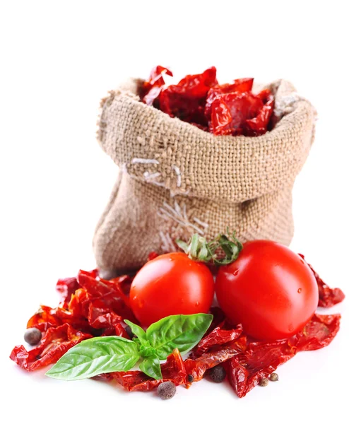 Sonnengetrocknete Tomaten in Säckebeutel und Basilikumblättern, isoliert auf weiß — Stockfoto