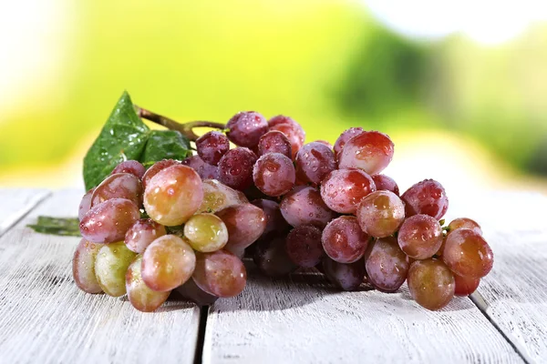 Bunch of ripe grape on wooden table on natural background — Stock Photo, Image