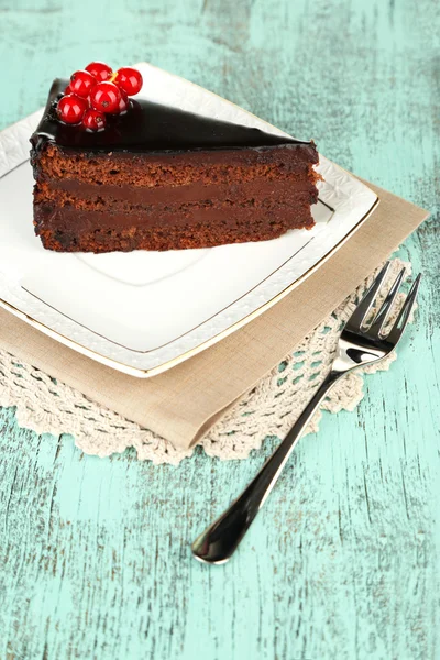 Choklad tårta med färska bär på plattan, färg trä bakgrund — Stockfoto