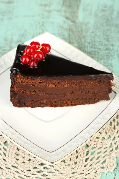 Schokoladenkuchen mit frischen Beeren auf Teller, auf farbigem Holzhintergrund — Stockfoto