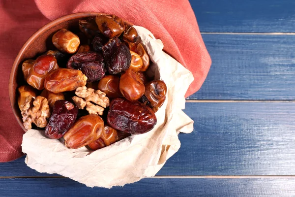 Tasty dates fruits in bowl, on blue wooden background — Stock Photo, Image