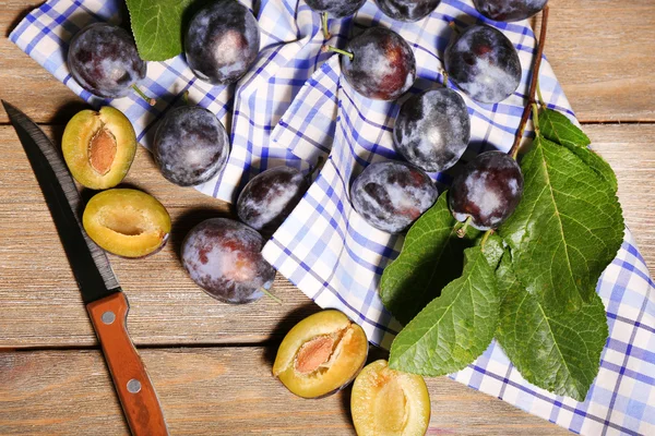 Ciruelas dulces maduras con hojas, sobre mesa de madera —  Fotos de Stock