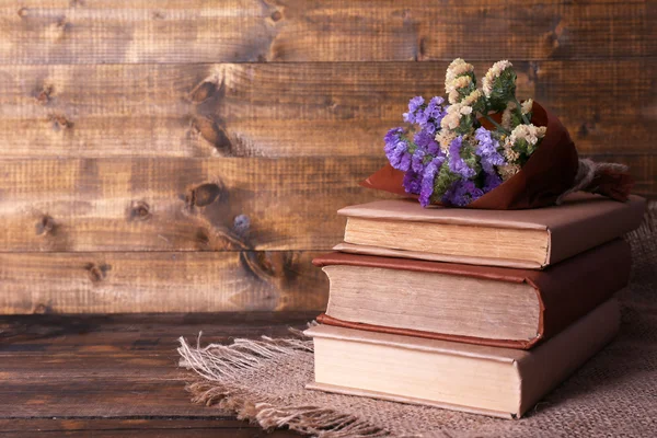 书籍和木板墙背景上的木桌上的餐巾的野花 — 图库照片
