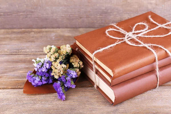 Boeken en wilde bloemen op houten tafel op houten muur achtergrond — Stockfoto