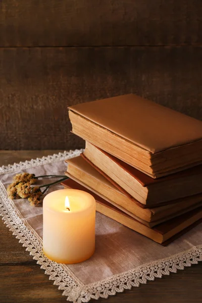 Boeken, bloemen en kaars op servet op houten tafel op houten muur achtergrond — Stockfoto