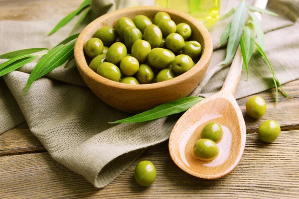 Green olives in bowl with leaves on table close-up — Stock Photo, Image