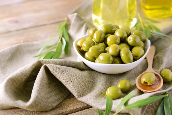 Olives vertes dans un bol avec des feuilles sur la table gros plan — Photo