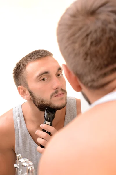 Jeune homme rasant sa barbe dans la salle de bain — Photo