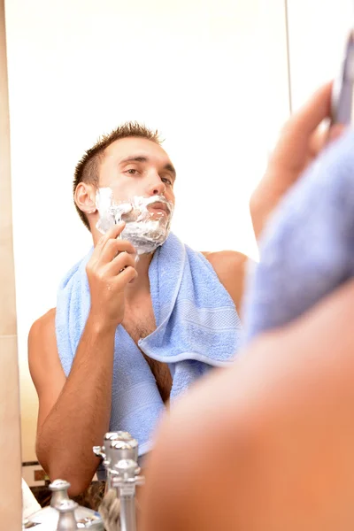 Jeune homme rasant sa barbe dans la salle de bain — Photo