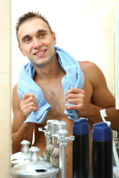 Young man shaving his beard in bathroom