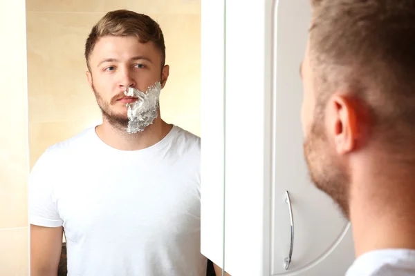 Young man shaving his beard in bathroom — Stock Photo, Image