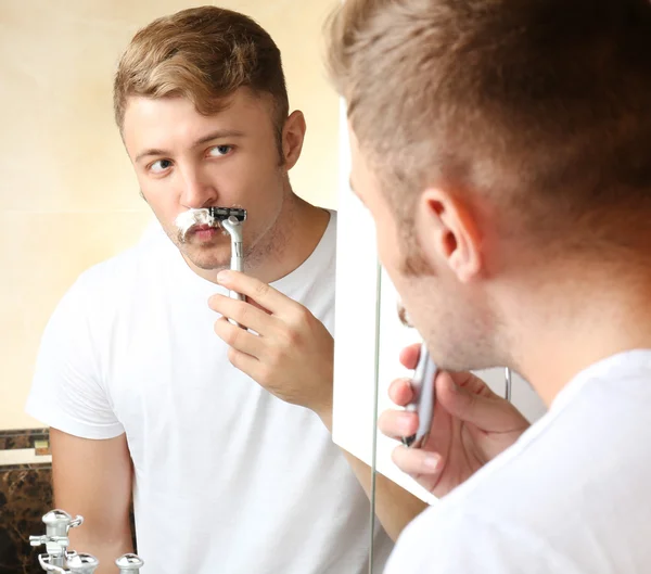 Mladý muž holení jeho vousy v koupelně — Stock fotografie