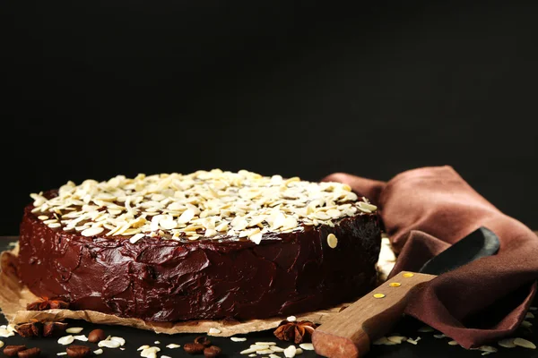 Leckere Schokoladenkuchen mit Mandeln, auf Holztisch, auf dunklem Hintergrund — Stockfoto