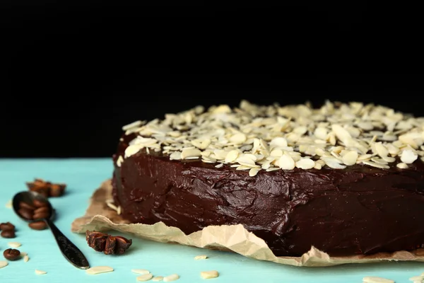 Sabroso pastel de chocolate con almendras, sobre mesa de madera, sobre fondo oscuro — Foto de Stock