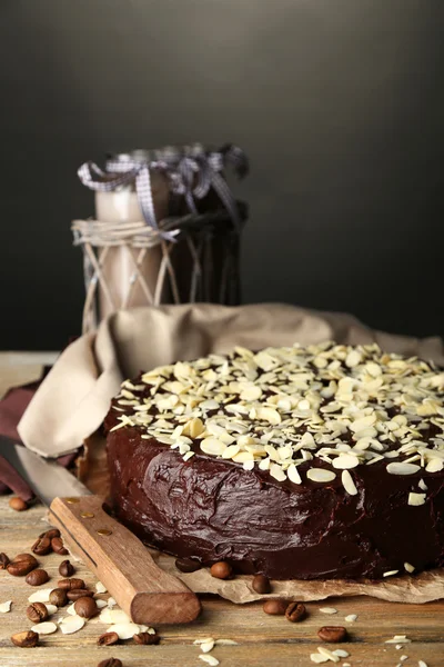 Sabroso pastel de chocolate con almendras, sobre mesa de madera, sobre fondo oscuro —  Fotos de Stock
