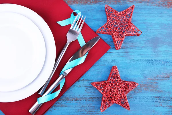 Piatti bianchi, forchetta, coltello e decorazione natalizia su tovagliolo su sfondo di legno — Foto Stock