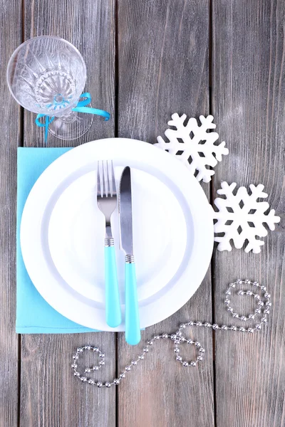 White plates, fork, knife, goblet and Christmas tree decoration on wooden background