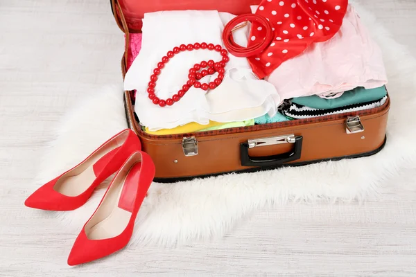 Female clothes in old suitcase on light background — Stock Photo, Image