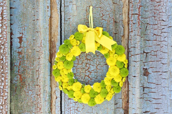 Beautiful wreath of flowers hanging on old wooden door — Stock Photo, Image