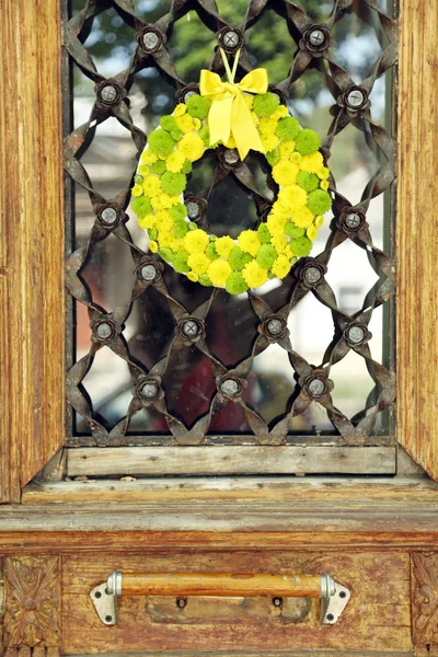 Mooie krans met bloemen hangen van oude houten deur — Stockfoto