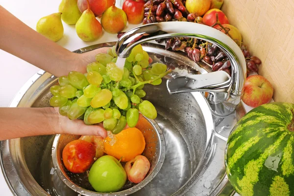 Wanita tangan mencuci anggur dan buah-buahan lainnya di colander di wastafel — Stok Foto