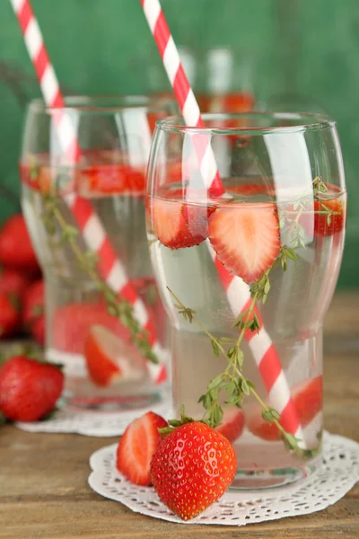 Tasty cool beverage with strawberries and thyme, on wooden background — Stock Photo, Image